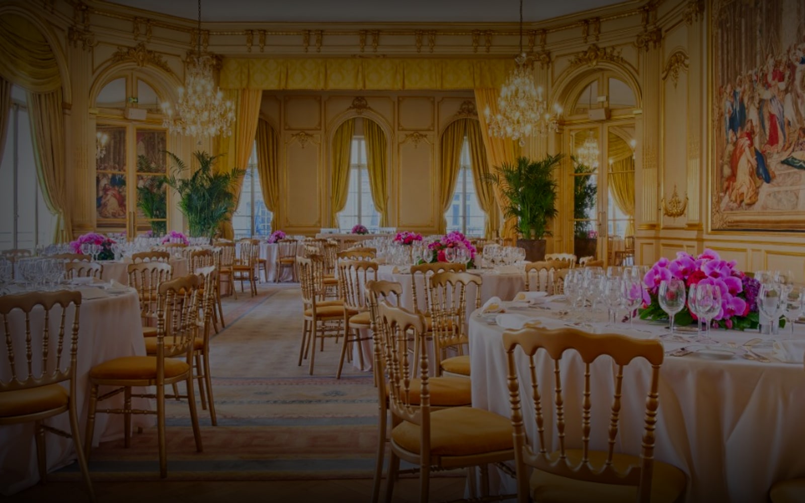 Salon de réception du Cercle de l'Union Interalliée dressé pour un dîner - tables rondes, chaises Chiavari dorées, lustres en cristal et bouquets d'orchidées