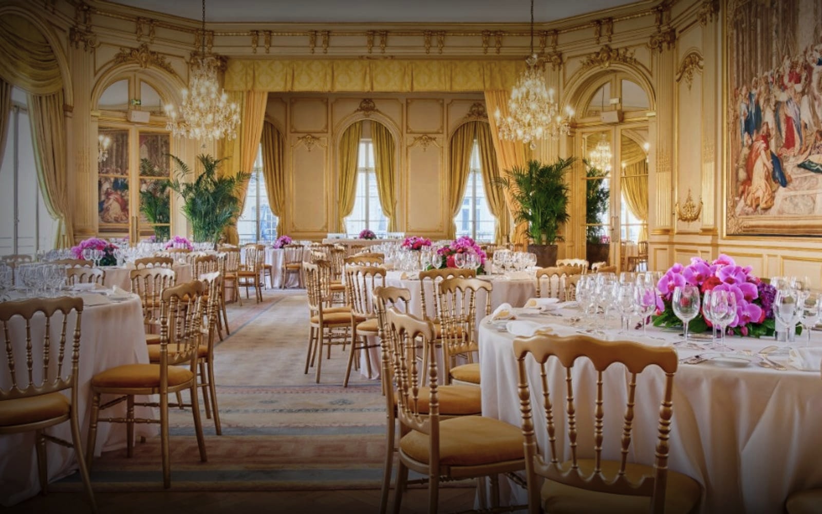Salon de réception du Cercle de l'Union Interalliée dressé pour un dîner - tables rondes, chaises Chiavari dorées, lustres en cristal et bouquets d'orchidées